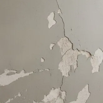 Pared con revoque fino agrietado y desprendido, ilustrando un error comun de aplicacion.