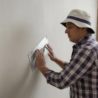 Albanil experimentado revisando el secado de una pared con revoque fino.
