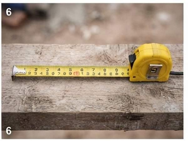 Cinta metrica metalica de 5 metros extendida sobre tabla de madera